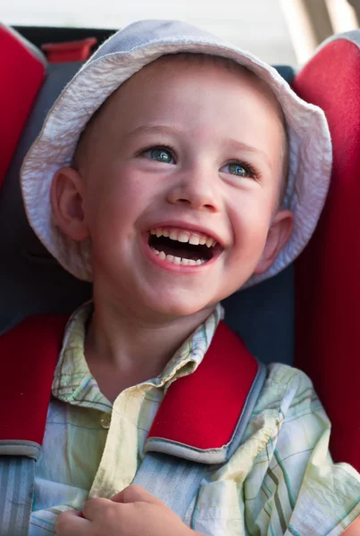 En skrattande pojke sitter i en booster Stockbild