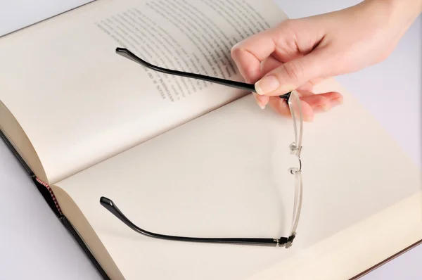 stock image Woman hand with eye glasses on book