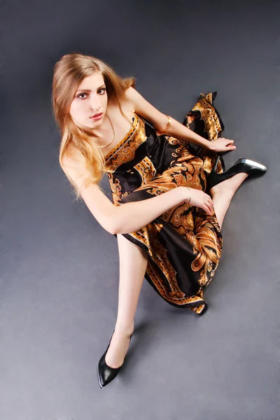 Mladá svůdná dívka v šatech, které sedí na podlaze — Stock fotografie