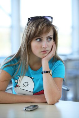 Young beautiful woman sitting at the table in cafe witn a phone clipart