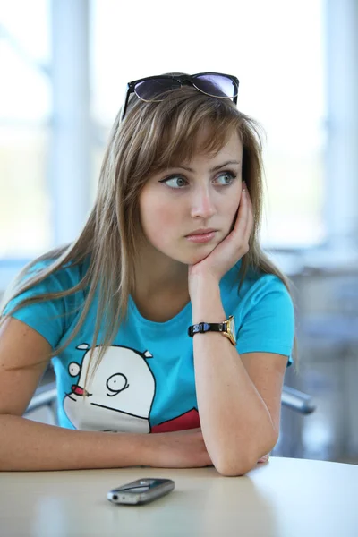 Молодая красивая женщина сидит за столом в кафе Витн телефон Стоковая Картинка