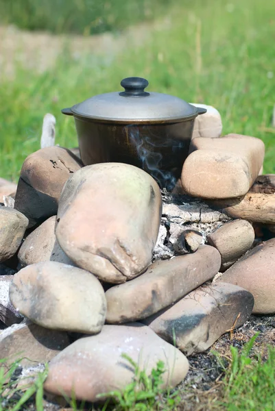 stock image Black saucepan on hot stones