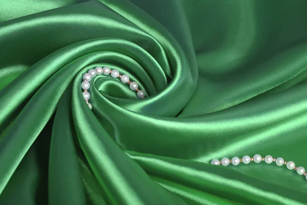 Жемчужные бусины на зеленом шелке — стоковое фото