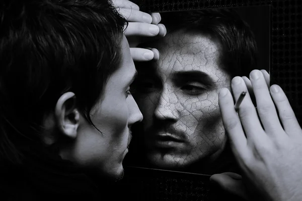 Hadsome młody człowiek z pęknięty twarz patrzy w lustro — Zdjęcie stockowe