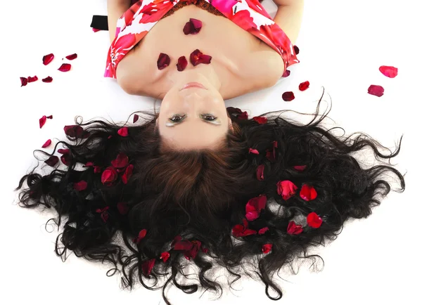Ung flicka ligger i kronbladen av rosor — Stockfoto