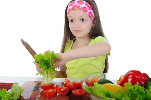 Kleines Mädchen schneidet Salat am Tisch — Stockfoto