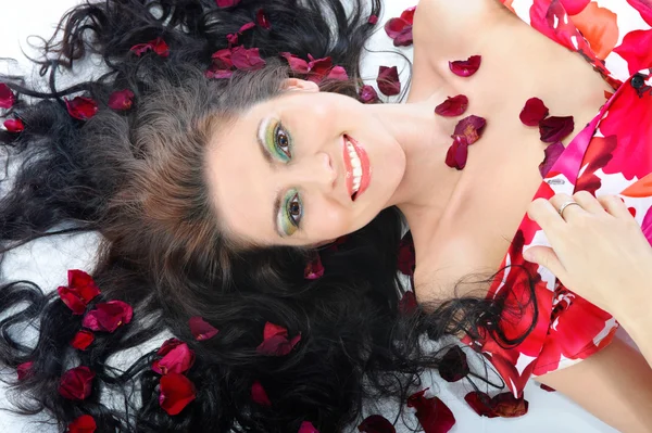 Vacker ung flicka i kronbladen av rosor — Stockfoto