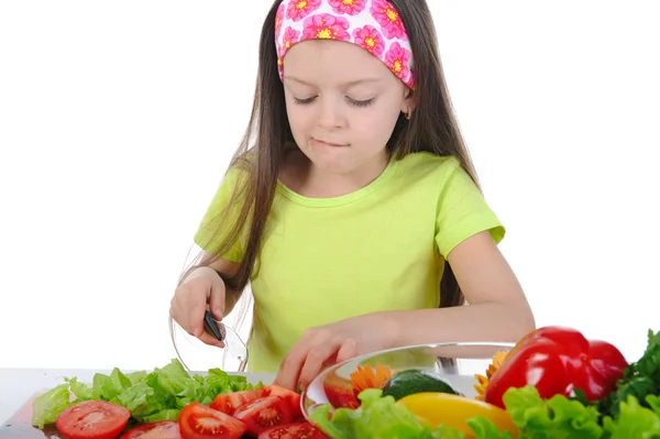 Kleines Mädchen schneidet Tomaten am Tisch — Stockfoto