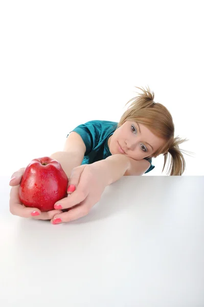 Menina bonita nova com uma maçã vermelha na mesa . — Fotografia de Stock
