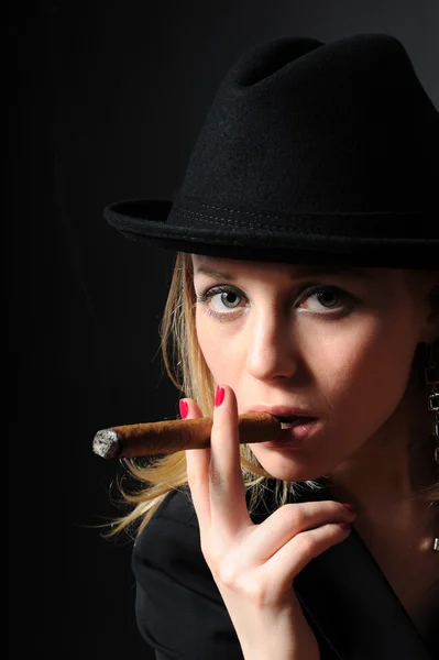 Vacker flicka i en hatt röka en cigarr Stockfoto