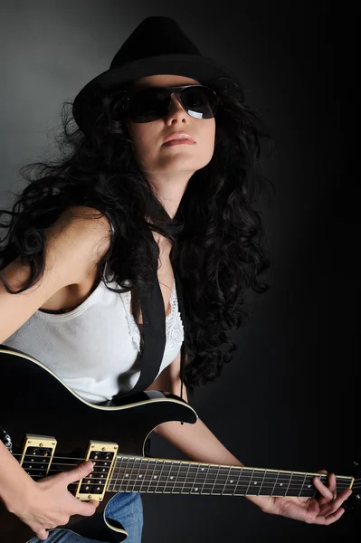 Κορίτσι σε ένα καπέλο και γυαλιά ηλίου με μια κιθάρα στα χέρια του — Φωτογραφία Αρχείου