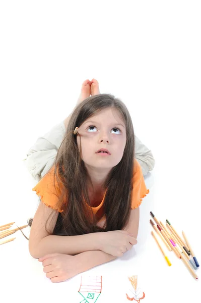 Pequena menina bonita desenha lápis deitado no chão . — Fotografia de Stock