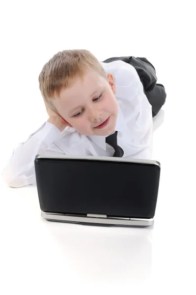 Kleine jongen liggend op de vloer met een laptop. — Stockfoto