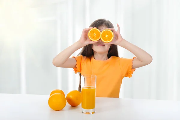 Menina na mesa com laranjas — Fotografia de Stock