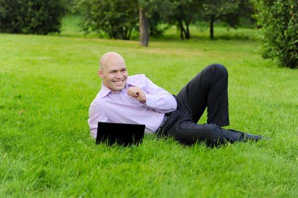 Άνθρωπος με φορητό υπολογιστή που βρίσκεται στο πράσινο γρασίδι — Φωτογραφία Αρχείου