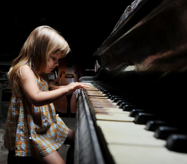 Flicka som leker på ett piano. — Stockfoto