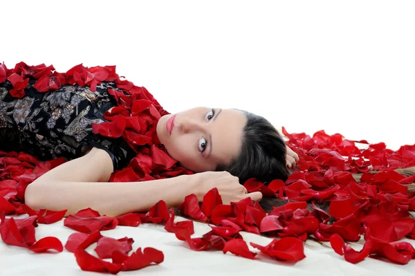 Красива брюнетка в пелюстках троянд — стокове фото