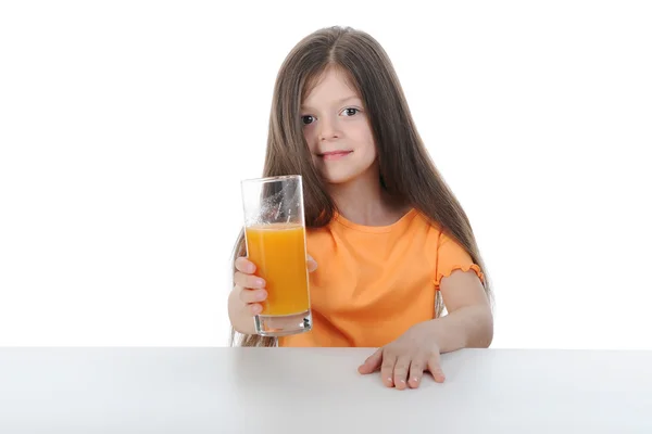 Menina com suco de laranja na mesa — Fotografia de Stock
