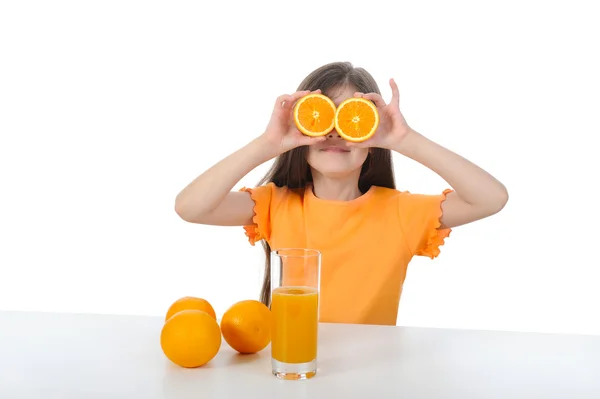 Девушка за столом с апельсинами и соком . — стоковое фото