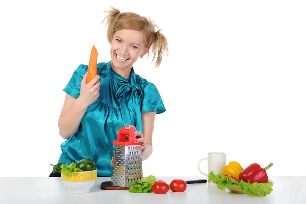 Młoda dziewczyna w kuchni tarcie marchewki. — Zdjęcie stockowe