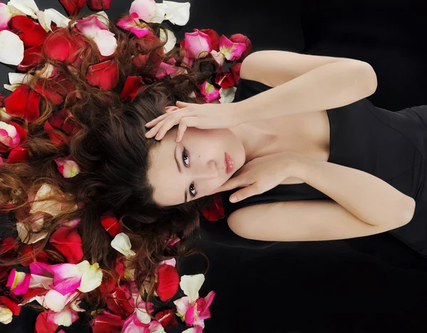 在玫瑰花瓣中的美丽黑发 — 图库照片