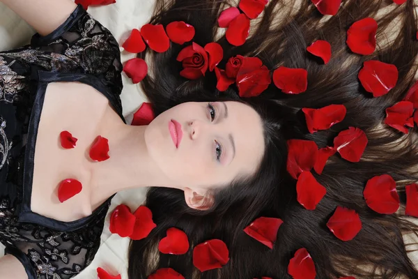 Beautiful brunette in rose petals — Stock Photo, Image