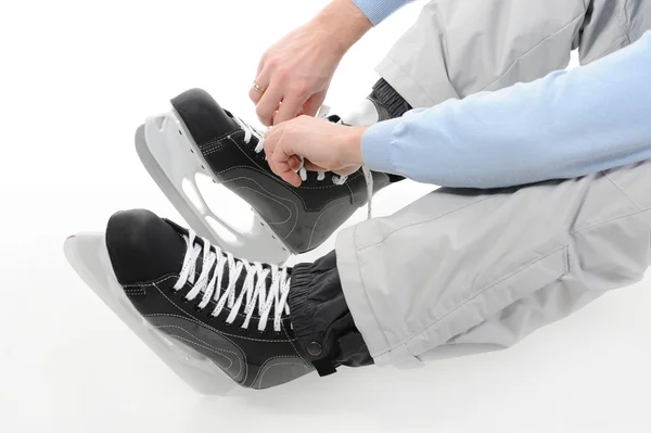 男はホッケーのスケートの靴ひもを結ぶします 白い背景で隔離 — ストック写真