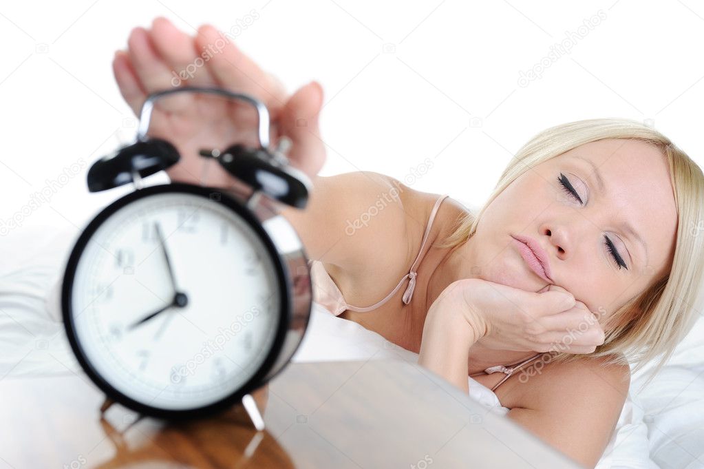 Sleepy woman turns off the alarm. Isolated on white background