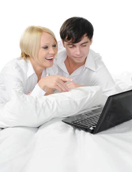若いカップルはベッドに横になっているラップトップを持つ 白い背景で隔離 — ストック写真