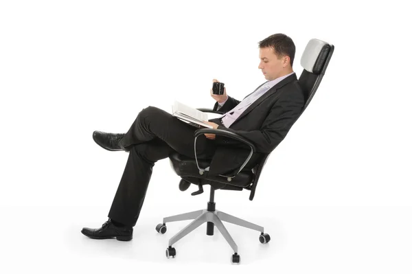 ビジネスマンは本を読んでと明るいオフィスで椅子に座って珈琲を飲みます 白い背景で隔離 — ストック写真