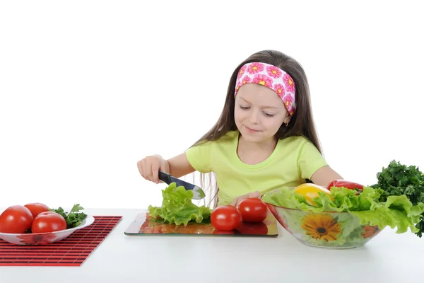 Little girl cut salad at the table — Stockfoto