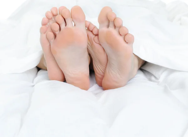 Close-up of the feet of a couple on the bed — Stock Photo, Image