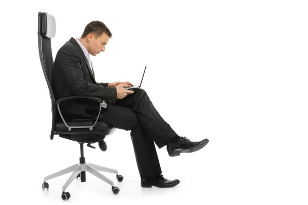 Businessman with a laptop sitting in a chair in a bright office. Isolated on white background