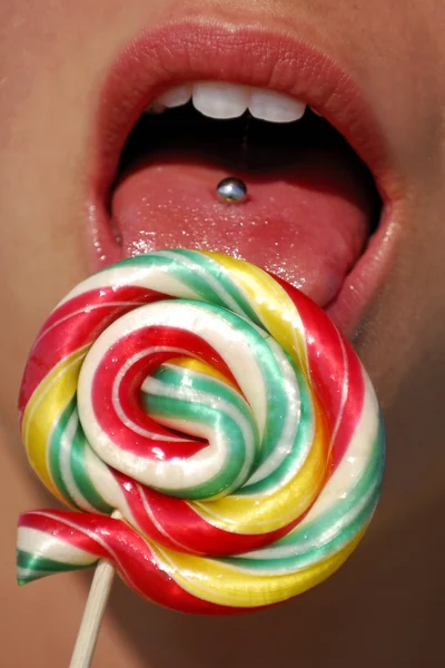 Pierced tongue licking lollipop