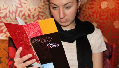 Woman looking in a menu in a restaurant clipart