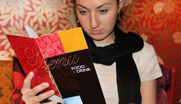 Frau schaut in Speisekarte eines Restaurants lizenzfreie Stockfotos