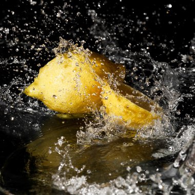 Fresh water drops on lemon on black background clipart