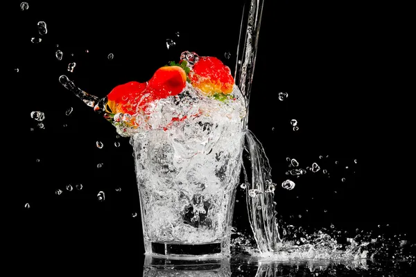 Spruzzare in un bicchiere con tre bacche rosse e ghiaccio su un dorso nero — Foto Stock
