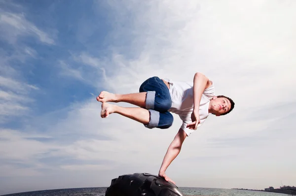 Genç adam sahilde gökyüzü arka plan atlama — Stok fotoğraf