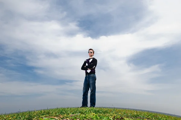 Junger Mann in den Wolken auf dem grünen Gras — Stockfoto