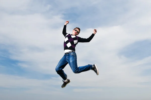 Ung man i glasögon hoppa i moln — Stockfoto