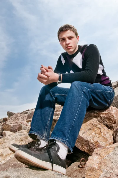 Jonge man op de rotsen in de wolken — Stockfoto
