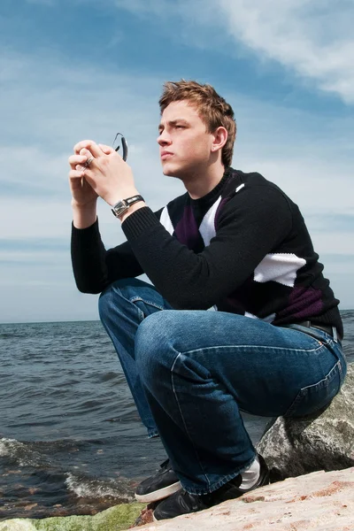 Young man on the rocks on the sea background — Stock Photo, Image