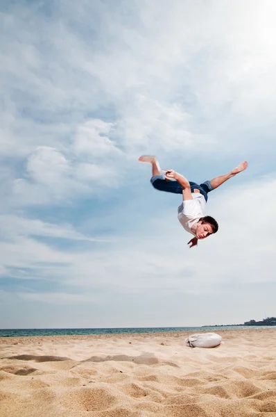 Den unge mannen hoppa på sand — Stockfoto