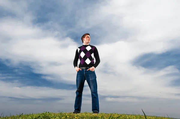 Молодой человек в облаках на зеленой траве — стоковое фото