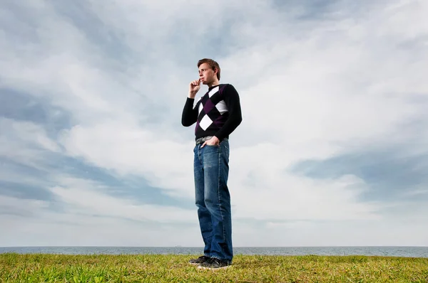 Mladý muž v oblacích na zelené trávě — Stock fotografie