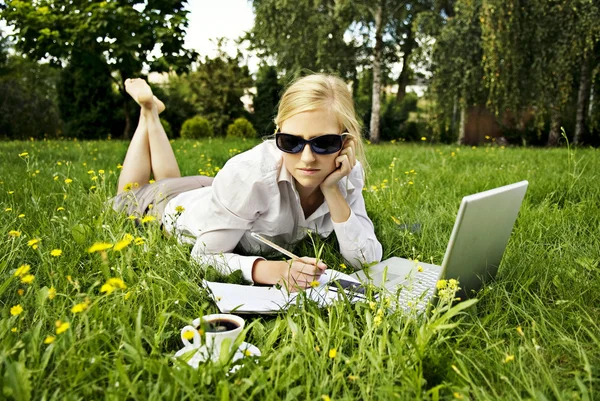 Young woman working outside on computer and drinking coffee — Stock Photo, Image