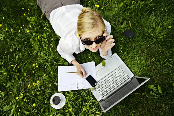Ung kvinna arbetar utanför på datorn och dricker kaffe — Stockfoto
