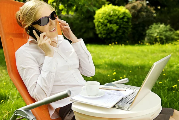 Young woman working outside on computer and talking — Stock Photo, Image