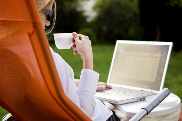 Mujer joven trabajando fuera en la computadora y tomando café —  Fotos de Stock
